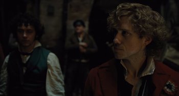 Movie still from “Les Misérables” (2012), directed by Tom Hooper – A man in a red jacket is smoking a cigarette; Close Up shot, Over the shoulder angle