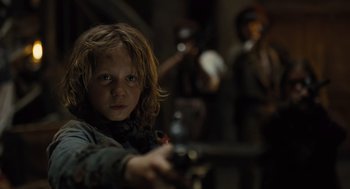 Movie still from “Les Misérables” (2012), directed by Tom Hooper – A young child holding a gun in a dark room; Close Up shot, Low angle