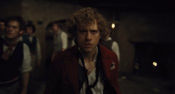 Movie still from “Les Misérables” (2012), directed by Tom Hooper – A man in a red jacket and a tie; Medium shot, Over the shoulder angle