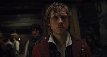 Movie still from “Les Misérables” (2012), directed by Tom Hooper – A man in a red jacket standing next to another man in a red jacket; Close Up shot, Over the shoulder angle