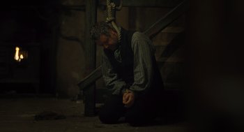 Movie still from “Les Misérables” (2012), directed by Tom Hooper – A man sitting on the ground with his hands tied to a rope; Medium shot, High angle