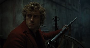 Movie still from “Les Misérables” (2012), directed by Tom Hooper – A man in a red jacket holding a gun; Close Up shot, Low angle