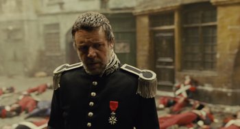 Movie still from “Les Misérables” (2012), directed by Tom Hooper – A man in a military uniform standing in front of a building; Medium shot, Over the shoulder angle