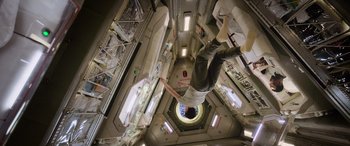 Movie still from “Life” (2017), directed by Daniel Espinosa – A man is hanging upside down in a space station; Wide shot, Overhead angle