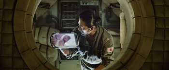 Movie still from “Life” (2017), directed by Daniel Espinosa – A man holding up a picture of a newborn baby; Close Up shot, Overhead angle