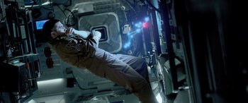 Movie still from “Life” (2017), directed by Daniel Espinosa – A person is standing in a space station; Medium shot, Overhead angle