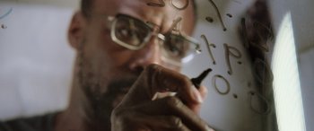 Movie still from “Life” (2017), directed by Daniel Espinosa – A man with glasses is writing on a glass window; Extreme Close Up shot, Low angle