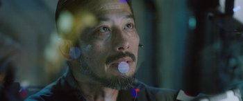 Movie still from “Life” (2017), directed by Daniel Espinosa – A person with a beard chewing gum; Close Up shot, Low angle