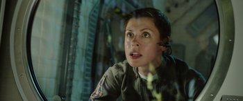 Movie still from “Life” (2017), directed by Daniel Espinosa – A woman with a headset on looking out of a window; Close Up shot, Low angle