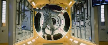 Movie still from “Life” (2017), directed by Daniel Espinosa – A man in a grey suit is jumping in the air; Wide shot, Overhead angle