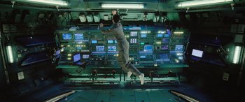 Movie still from “Life” (2017), directed by Daniel Espinosa – A man is jumping in the air in front of a control room; Wide shot, Overhead angle