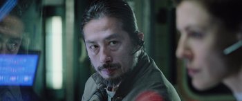 Movie still from “Life” (2017), directed by Daniel Espinosa – A person with a beard; Close Up shot, Over the shoulder angle