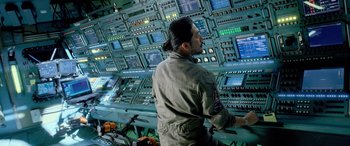 Movie still from “Life” (2017), directed by Daniel Espinosa – A man standing in front of a wall with lots of computer screens; Medium shot, Over the shoulder angle