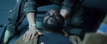 Movie still from “Life” (2017), directed by Daniel Espinosa – A man laying on the ground while another person is holding his hands over his head; Close Up shot, Overhead angle
