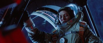 Movie still from “Life” (2017), directed by Daniel Espinosa – A woman in a space suit holding a bottle; Medium shot, Overhead angle