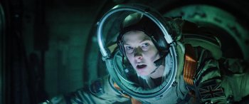 Movie still from “Life” (2017), directed by Daniel Espinosa – A woman in a space suit looking into a mirror; Medium shot, Low angle