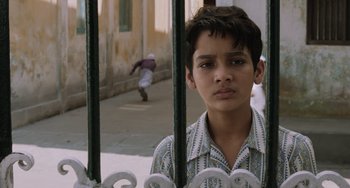 Movie still from “Life of Pi” (2012), directed by Ang Lee – A young boy standing behind a fence looking at the camera; Close Up shot, Low angle