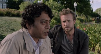 Movie still from “Life of Pi” (2012), directed by Ang Lee – Two men sitting on a park bench looking at each other with trees in the background; Close Up shot, Over the shoulder angle