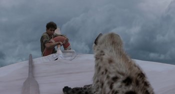 Movie still from “Life of Pi” (2012), directed by Ang Lee – A man sitting on top of a bed next to an animal; Wide shot, Over the shoulder angle
