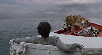 Movie still from “Life of Pi” (2012), directed by Ang Lee – A man sitting on a boat looking at a tiger on the water; Wide shot, Low angle