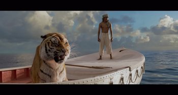 Movie still from “Life of Pi” (2012), directed by Ang Lee – A man standing on top of a beach next to a tiger; Wide shot, Low angle