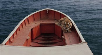 Movie still from “Life of Pi” (2012), directed by Ang Lee – A tiger sitting on the back end of a boat in the water; Extreme Wide shot, High angle