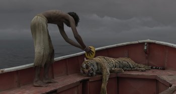 Movie still from “Life of Pi” (2012), directed by Ang Lee – A man holding a yellow frisbee next to a tiger; Wide shot, Low angle