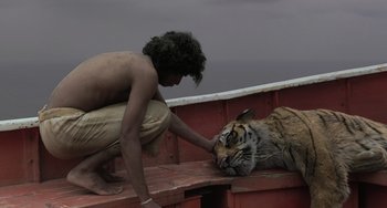Movie still from “Life of Pi” (2012), directed by Ang Lee – A man petting the head of a tiger on a boat; Medium shot, Overhead angle