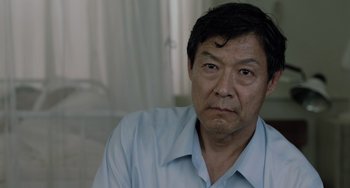 Movie still from “Life of Pi” (2012), directed by Ang Lee – An asian man with a goatee sitting in a room; Close Up shot, Over the shoulder angle