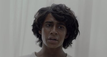 Movie still from “Life of Pi” (2012), directed by Ang Lee – A young man with long black hair stares into the camera; Close Up shot, Low angle
