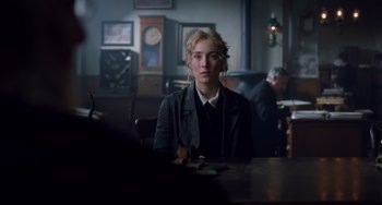 Movie still from “Little Women” (2019), directed by Greta Gerwig – A woman sitting at a table in front of a clock; Medium shot, Over the shoulder angle