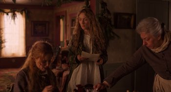 Movie still from “Little Women” (2019), directed by Greta Gerwig – A woman standing in front of a group of people holding papers; Medium shot, Over the shoulder angle