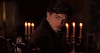 Movie still from “Little Women” (2019), directed by Greta Gerwig – A young man standing in front of a group of lit candles; Close Up shot, Over the shoulder angle