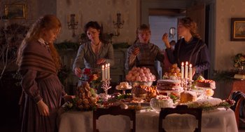 Movie still from “Little Women” (2019), directed by Greta Gerwig – A group of people standing around a table filled with food; Medium shot, High angle