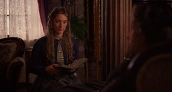 Movie still from “Little Women” (2019), directed by Greta Gerwig – A young woman sitting on the floor reading a book; Medium shot, Over the shoulder angle