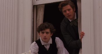 Movie still from “Little Women” (2019), directed by Greta Gerwig – Two young men are looking out of a window; Medium shot, Low angle