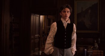 Movie still from “Little Women” (2019), directed by Greta Gerwig – A young man wearing a black vest standing in a room; Medium shot, Low angle