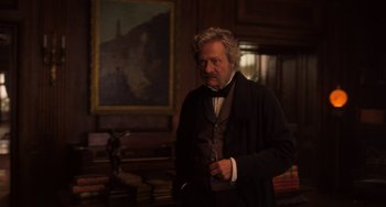 Movie still from “Little Women” (2019), directed by Greta Gerwig – An older man standing in front of a painting in a living room; Medium shot, Low angle