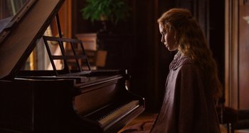 Movie still from “Little Women” (2019), directed by Greta Gerwig – A young girl sitting in front of an upright piano; Medium shot, Over the shoulder angle