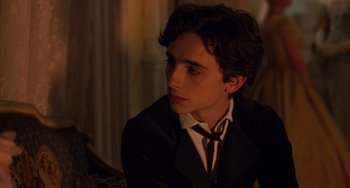 Movie still from “Little Women” (2019), directed by Greta Gerwig – A young man in a suit and tie looking to his left; Close Up shot, Over the shoulder angle