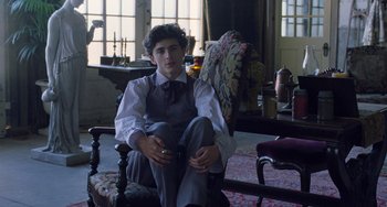 Movie still from “Little Women” (2019), directed by Greta Gerwig – A young man sitting on a chair in a living room; Medium shot, Low angle