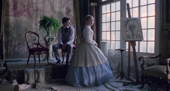Movie still from “Little Women” (2019), directed by Greta Gerwig – A man and a woman dressed in period clothing in front of an easel; Medium shot, Over the shoulder angle