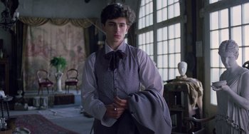 Movie still from “Little Women” (2019), directed by Greta Gerwig – A young man in a suit and bow tie in a room; Medium shot, Low angle
