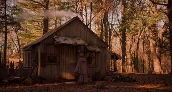 Movie still from “Little Women” (2019), directed by Greta Gerwig – A woman standing in front of a wooden cabin; Wide shot, Over the shoulder angle
