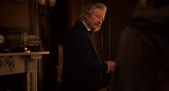 Movie still from “Little Women” (2019), directed by Greta Gerwig – An older man wearing a suit and tie in a room; Medium shot, Over the shoulder angle