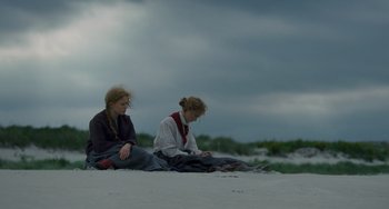 Movie still from “Little Women” (2019), directed by Greta Gerwig – Two women sitting on the beach looking at a laptop; Wide shot, Over the shoulder angle