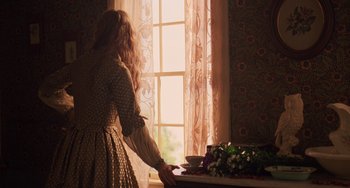 Movie still from “Little Women” (2019), directed by Greta Gerwig – A woman standing in front of a window with a cup of tea; Medium shot, Over the shoulder angle