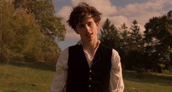 Movie still from “Little Women” (2019), directed by Greta Gerwig – A young man wearing a black vest standing in a field; Close Up shot, Low angle