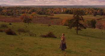 Movie still from “Little Women” (2019), directed by Greta Gerwig – A woman standing on top of a grass covered field; Extreme Wide shot, High angle