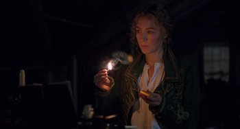 Movie still from “Little Women” (2019), directed by Greta Gerwig – A woman holding a lit candle in a dark room; Medium shot, Low angle